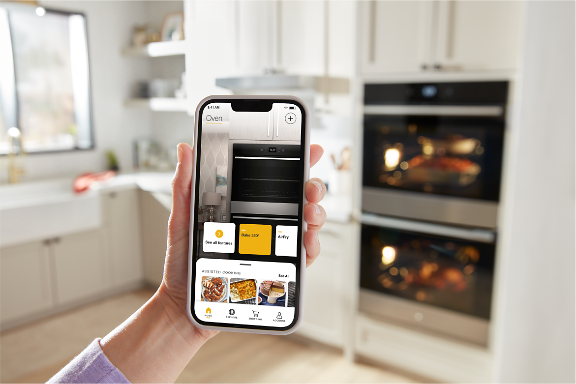 Hands control a Whirlpool® Smart Wall Oven via the Whirlpool® App
