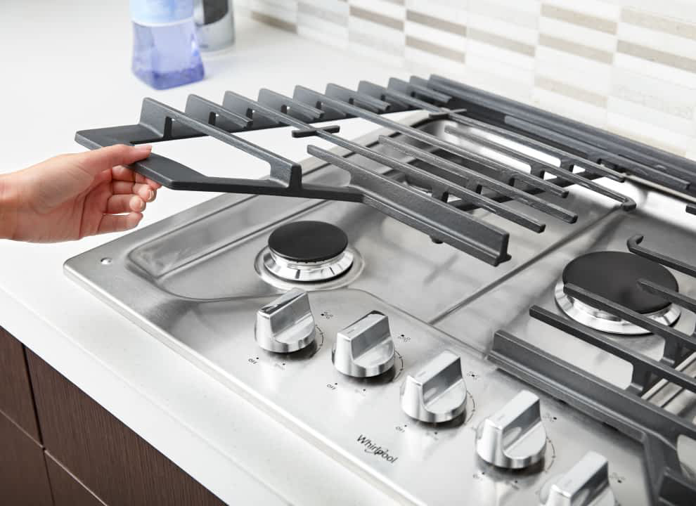 Hand lifting EZ-2-Lift™ Hinged Cast-Iron Grates on a Whirlpool® Cooktop