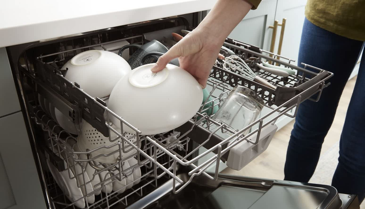 A person placing a white bowl in the 3rd Rack of a Whirlpool® Dishwasher