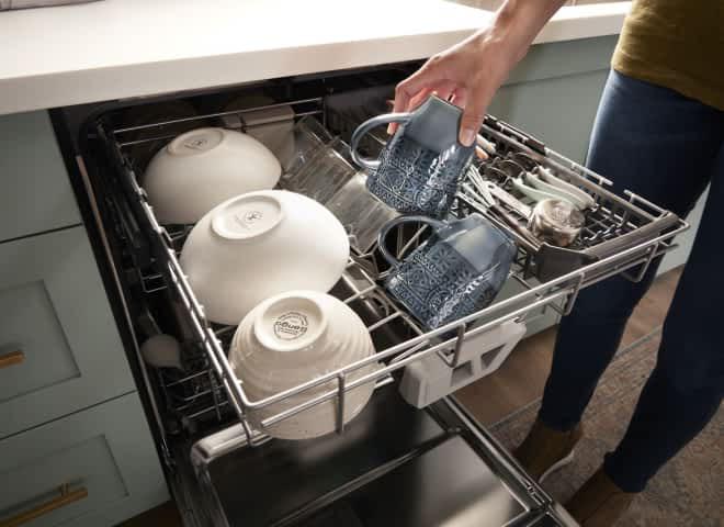 A hand loading a coffee mug in the 3rd Rack with Extra Wash Action