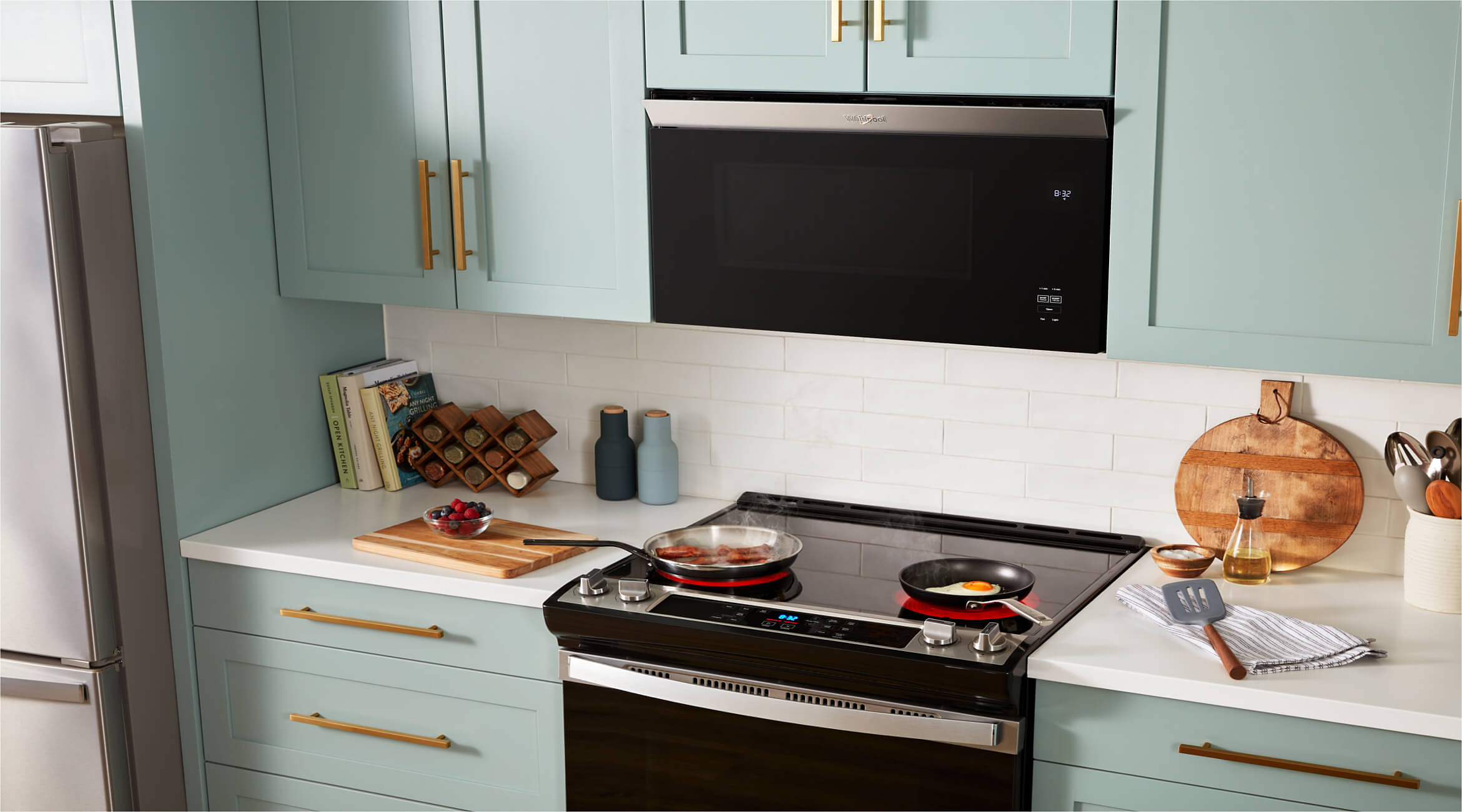 Whirlpool® Flush Built-In Over-the-Range Microwave and Slide-In Electric Range in a kitchen with light sage green cabinets.