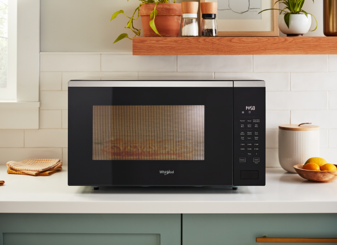 A Whirlpool® Microwave on a kitchen counter with food inside