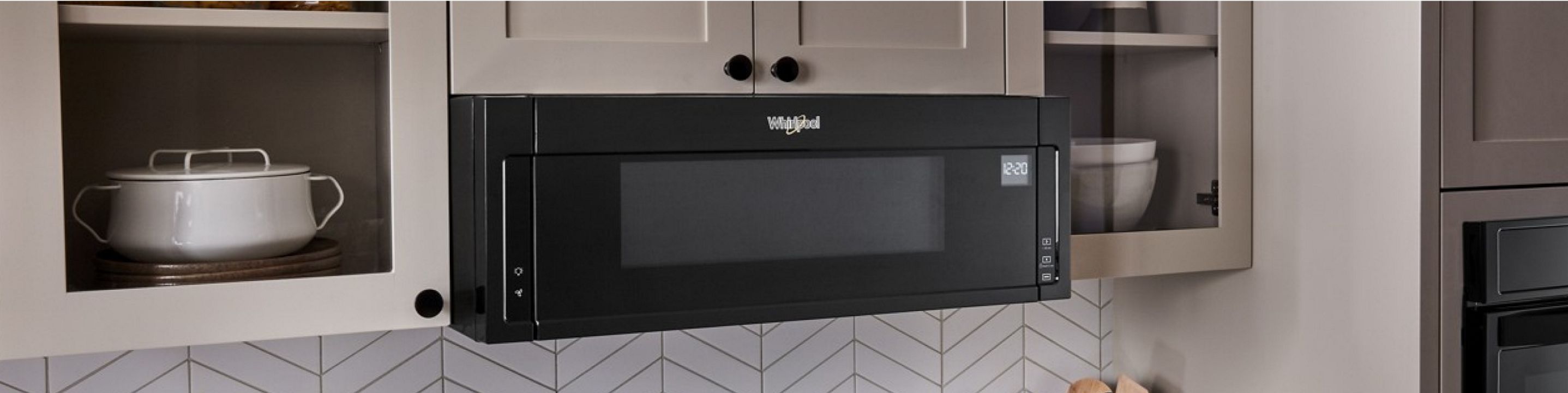 A Whirlpool® Low Profile Microwave in a sleek, white, modern kitchen