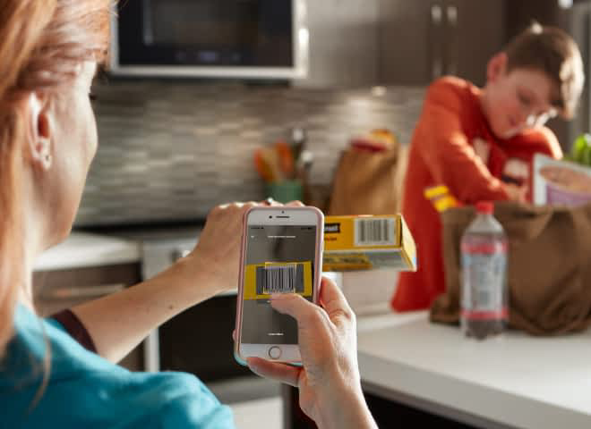 A person scans a barcode onto their smartphone using the Whirlpool® App. 