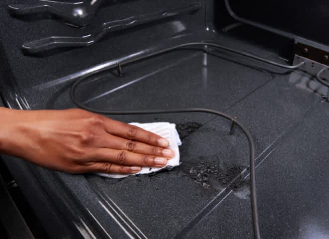 Hands wiping up soil inside a Whirlpool® Oven