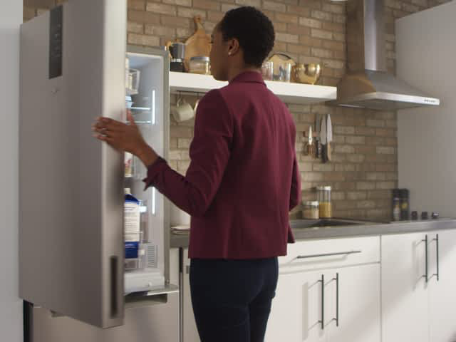 A woman opens a Whirlpool® Bottom Freezer Refrigerator with a Fingerprint-Resistant Stainless Finish