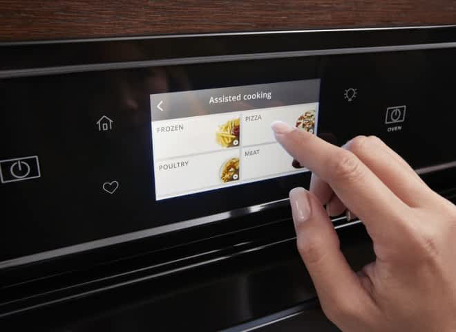 Hands use the touchscreen on a Whirlpool® Wall Oven