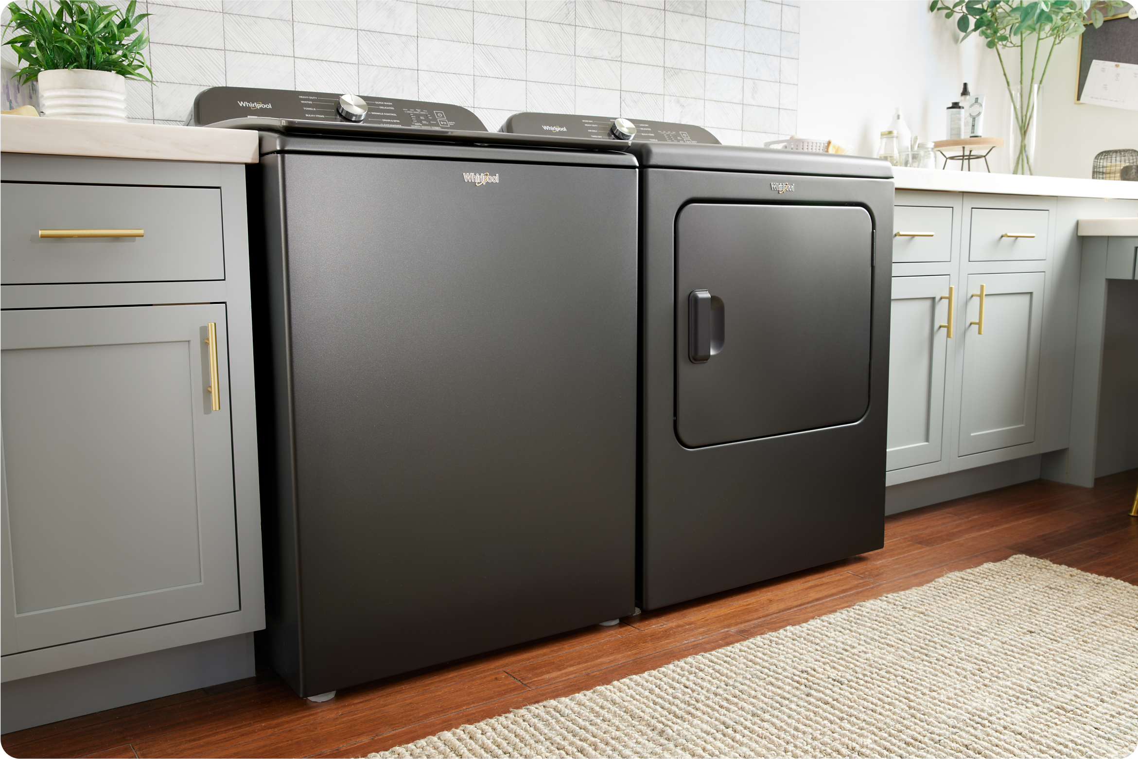 A Whirlpool® Top Load Washer & Dryer Set in laundry room with light cabinets