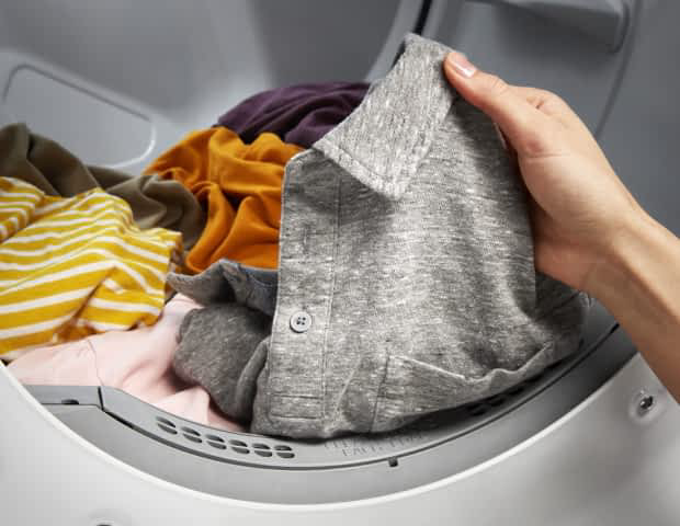 Hands hold up a shirt in a Whirlpool® Dryer