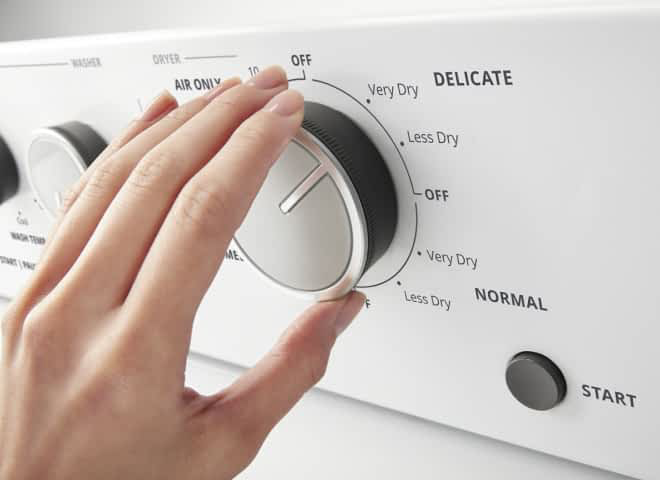 A hand turns a knob on a Whirlpool® Stacked Laundry Center