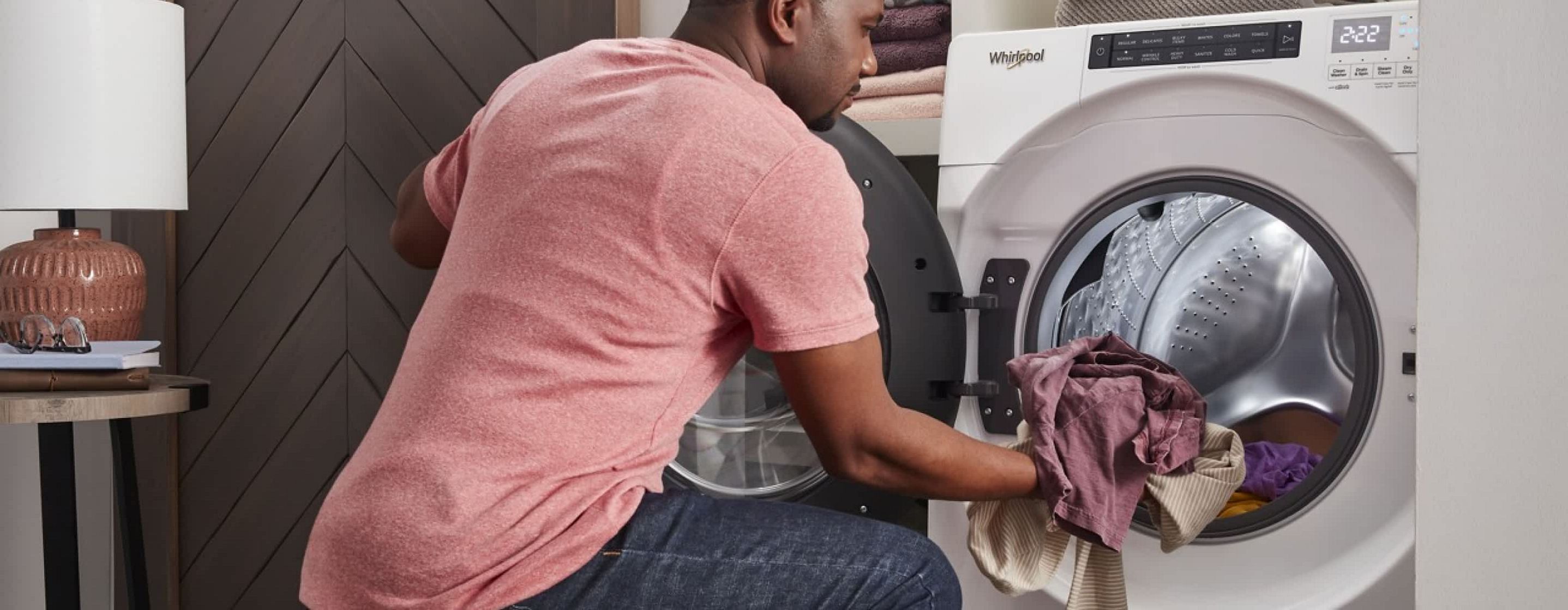A man unloads laundry from a Whirlpool® Top Load Matching Dryer