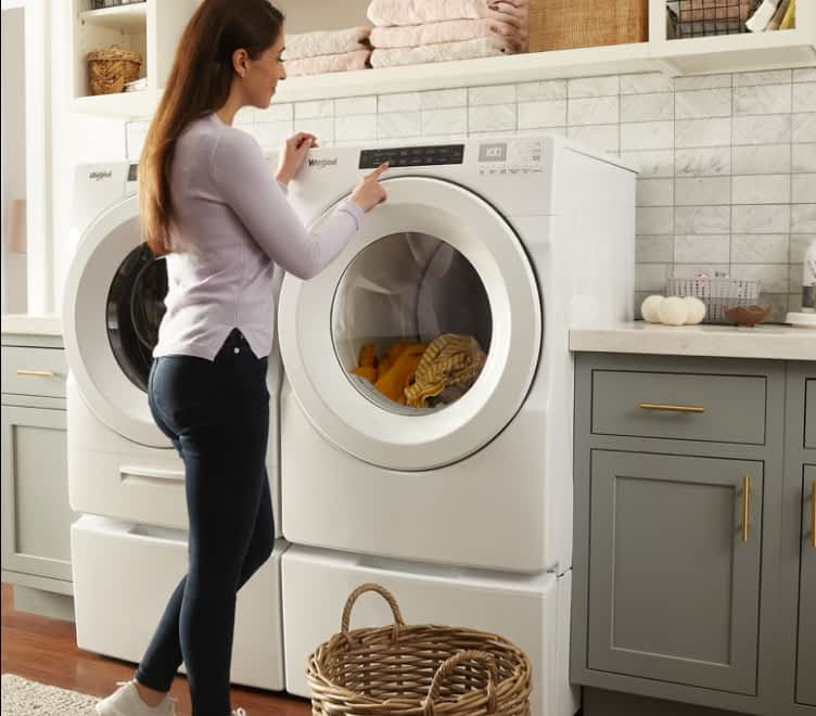 A woman loading laundry in a Whirlpool® Dryer