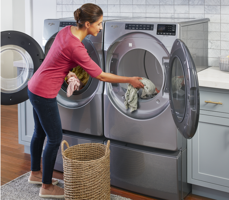 A woman loading laundry in a Whirlpool® Dryer