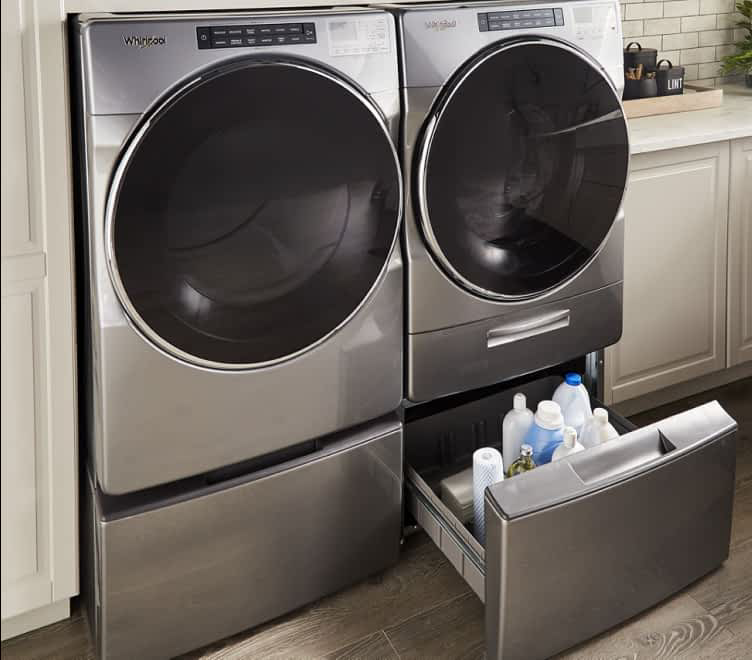 A Whirlpool® Front Load Washer and Dryer side-by-side on top of laundry pedestals