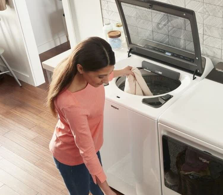 A person loading laundry into a Whirlpool® Washer