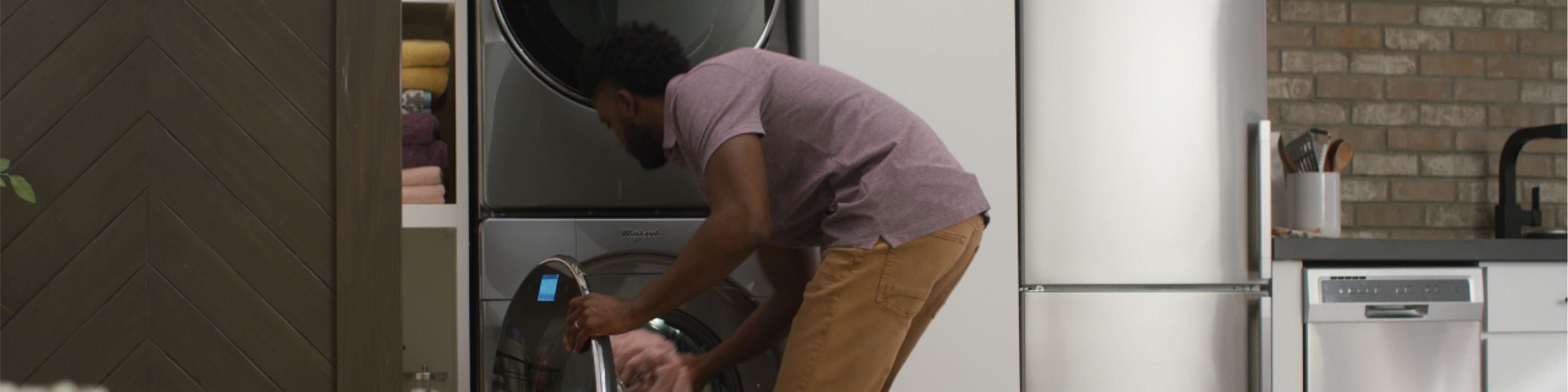 A person loads laundry into a Whirlpool® Stacked Washer & Dryer
