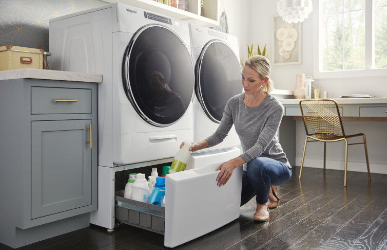 A person putting an item into a pedestal drawer on a Whirlpool® Front Load Washer