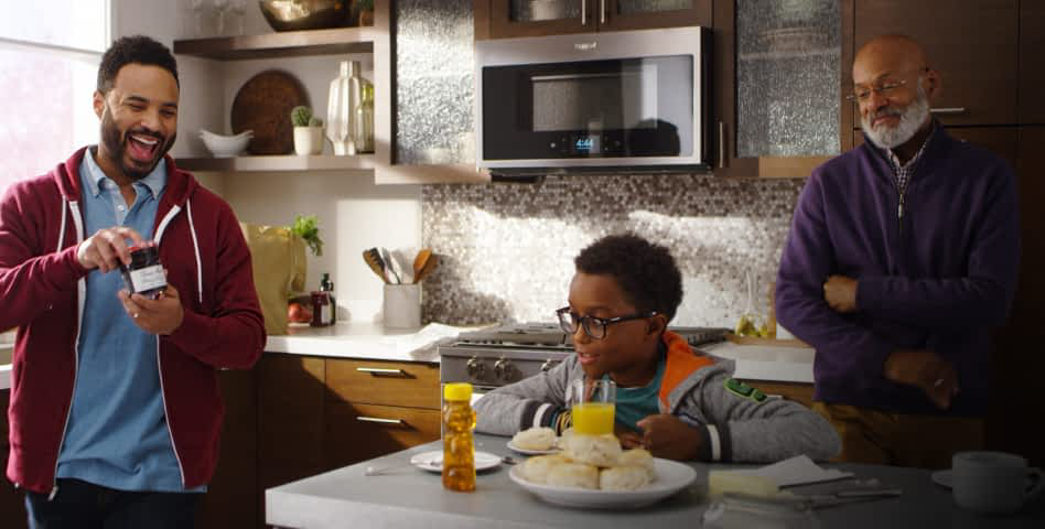 A multi-generational family eating biscuits in the kitchen, with the Home Heartbeat Appliance Blog logo