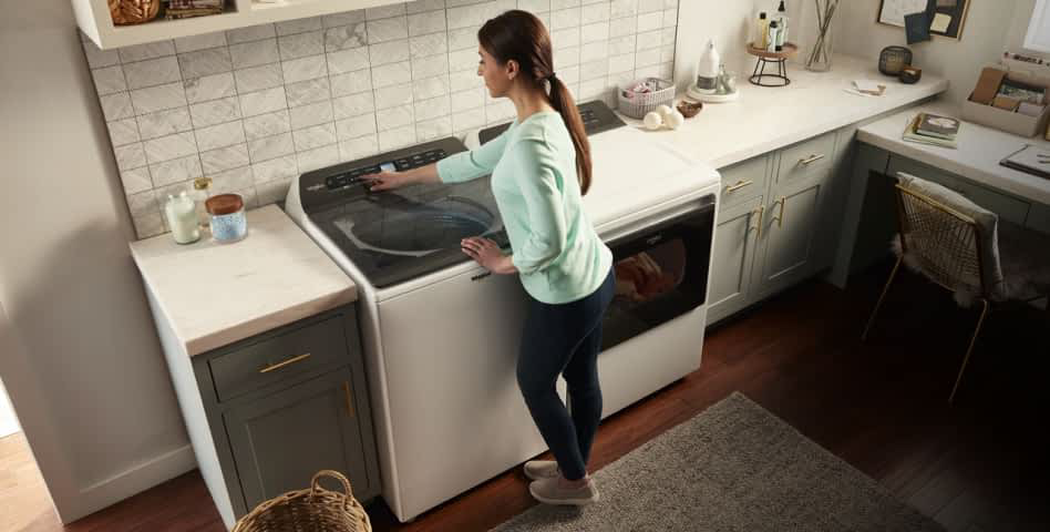 A woman running a Whirlpool® Top Load Washing Machine