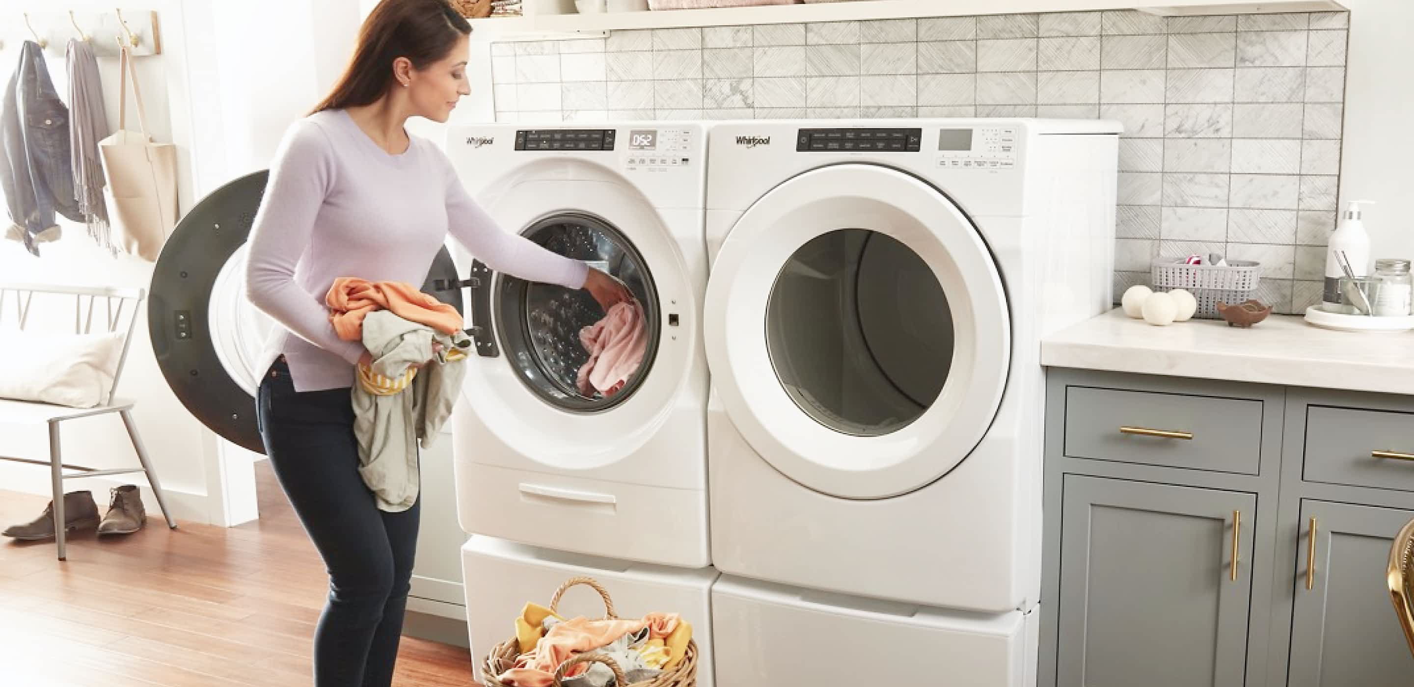 A woman loading laundry into a Whirlpool® Front Load Washer and Dryer Pair