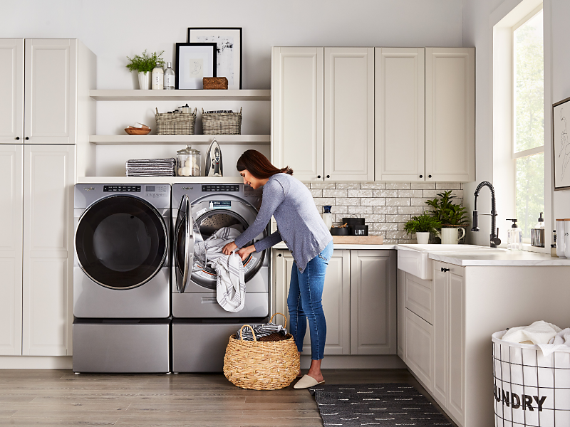 Woman loading laundry in a stainless steel Whirlpool® dryer