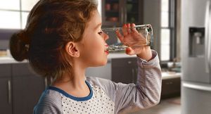 Jeune fille buvant dans un verre d’eau