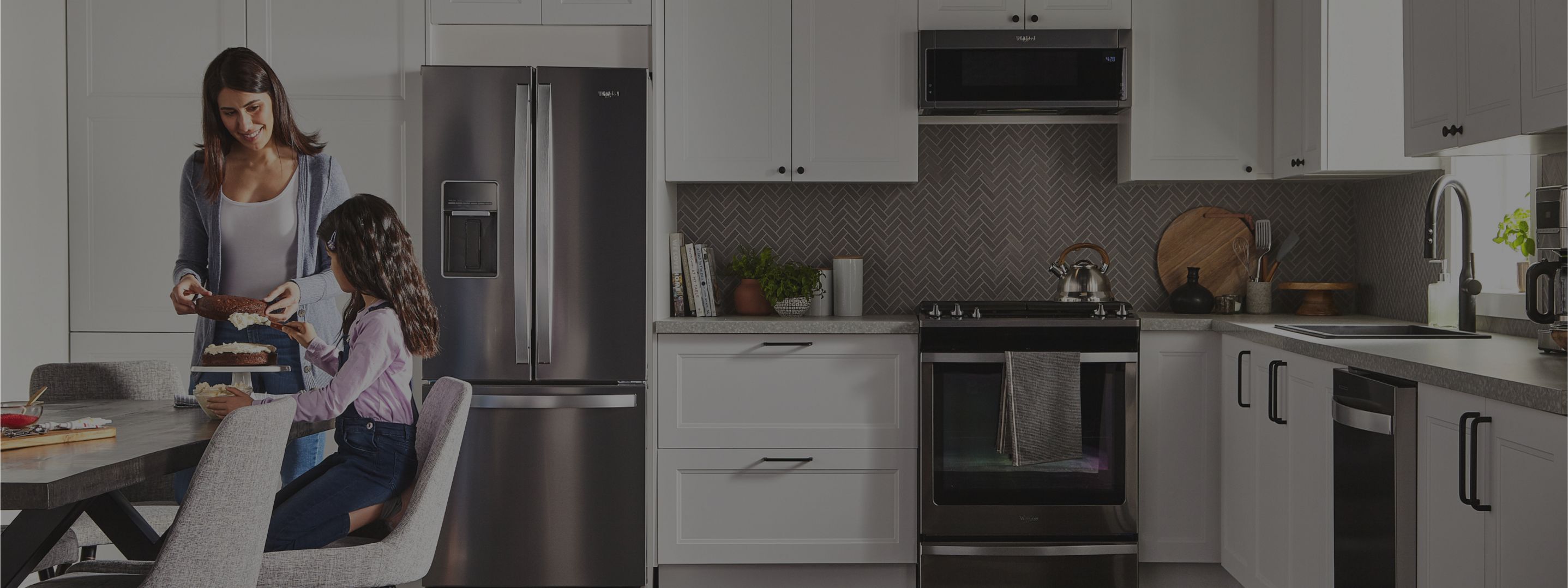 An adult and a child frosting a cake in a kitchen with Whirlpool® Appliances