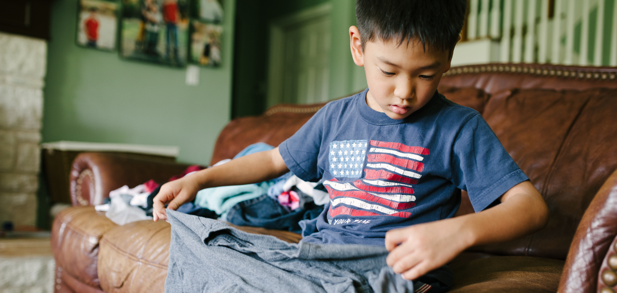 Young child helping fold laundry on the couch