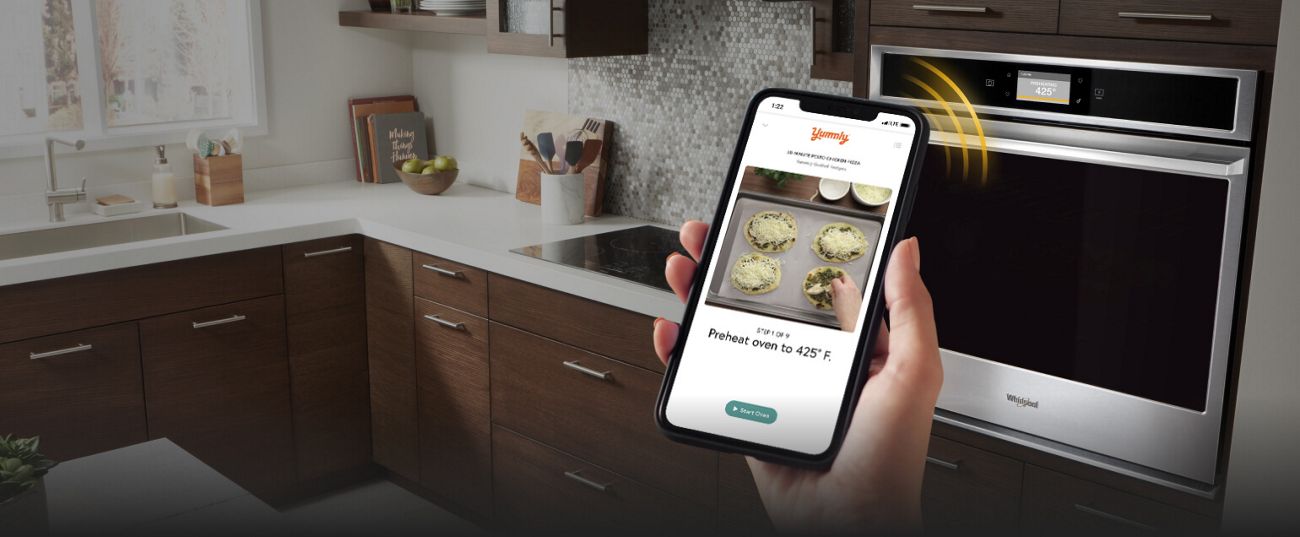 Smartphone sending cooking instructions from the Yummly® app to select Whirlpool® Smart Wall Ovens