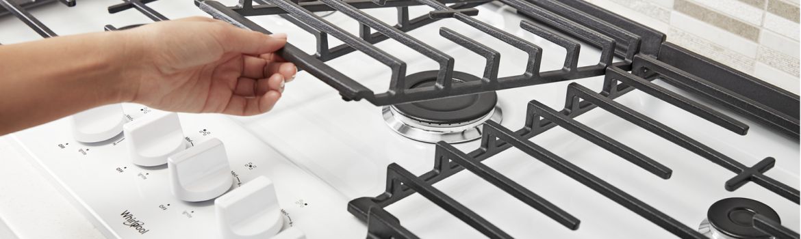 Hands lifting up the hinges on a Whirlpool® Gas Cooktop
