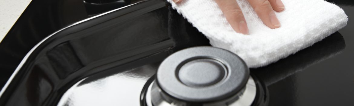 Hands wiping down the top of a Whirlpool® Gas Cooktop