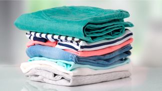 Una Lavadora de carga superior Whirlpool en color negro, con ropa muy colorida siendo lavanda dentro de la lavadora.