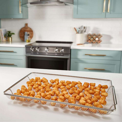 An air fry basket with cooked tater tots