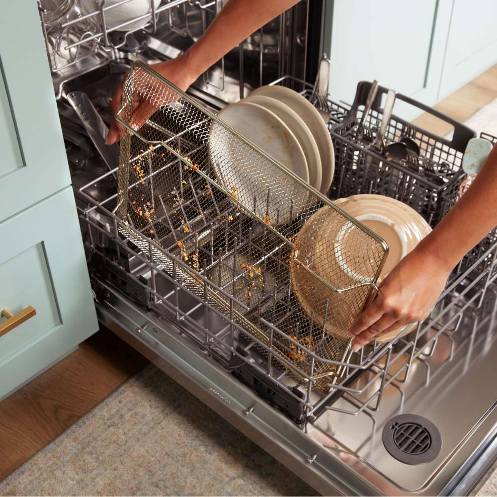 Homeowner loading an air fryer basket and other items into a dishwasher