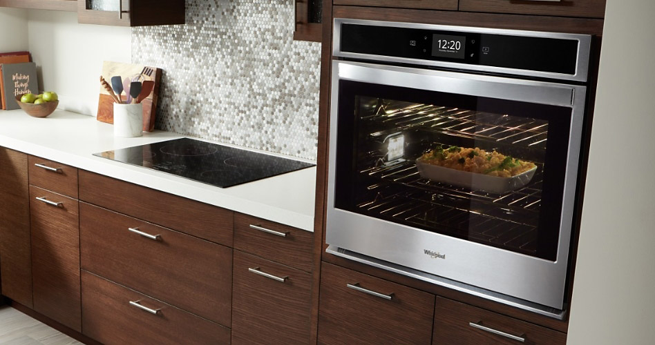 A Whirlpool stainless steel wall oven in a dark brown wood cabinet.