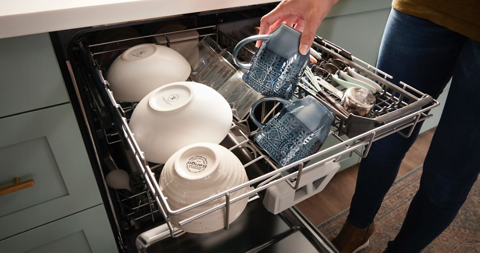 Woman loading Whirlpool dishwasher with third rack