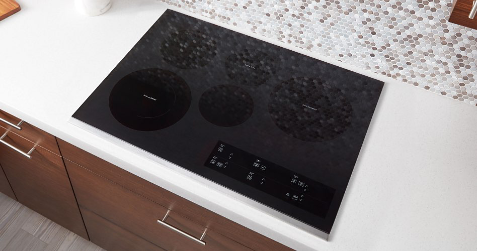 A Whirlpool Induction Cooktop. On the counter is a bowl of apples and an oil bottle.