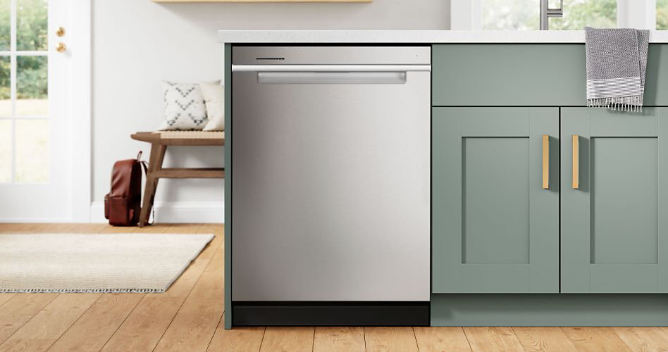 A Whirlpool dishwasher next to green cabinets that are under a sink. Next to the dishwasher is the front door and a bench with pillows on top and a backpack leaning against it.