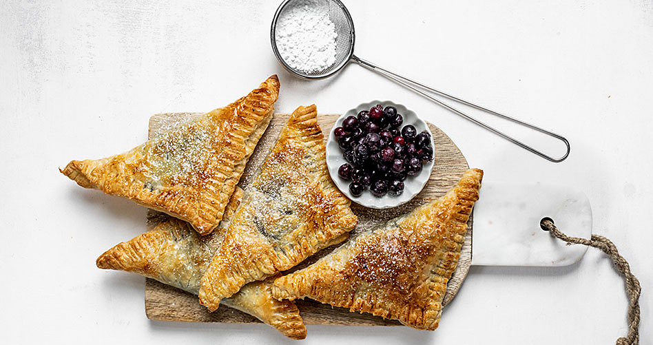 A serving of four berry turnovers with powdered sugar