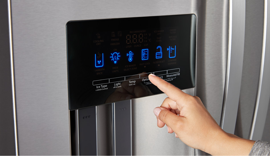 A homeowner is seen using the tap touch controls on a Whirlpool refrigerator