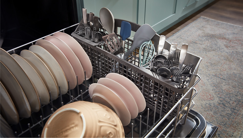 Various dishes and silverware in the bottom rack of a dishwasher