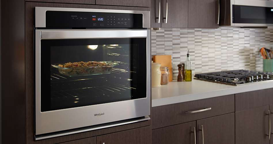 A stainless steel Whirlpool single wall oven built into a kitchen cabinet