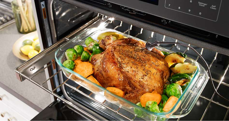 A whole chicken and vegetables that have been cooked in a Whirlpool wall oven