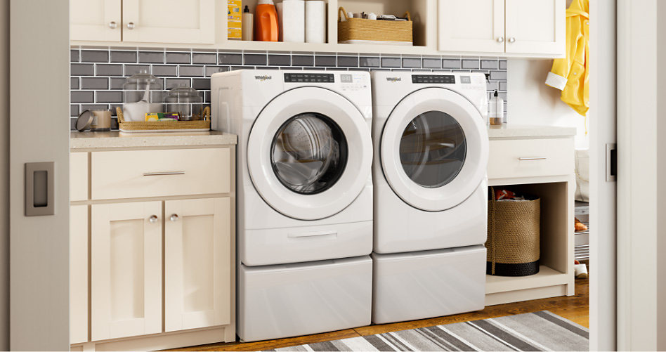 A laundry room with a white front loading washer and dryer on pedestals