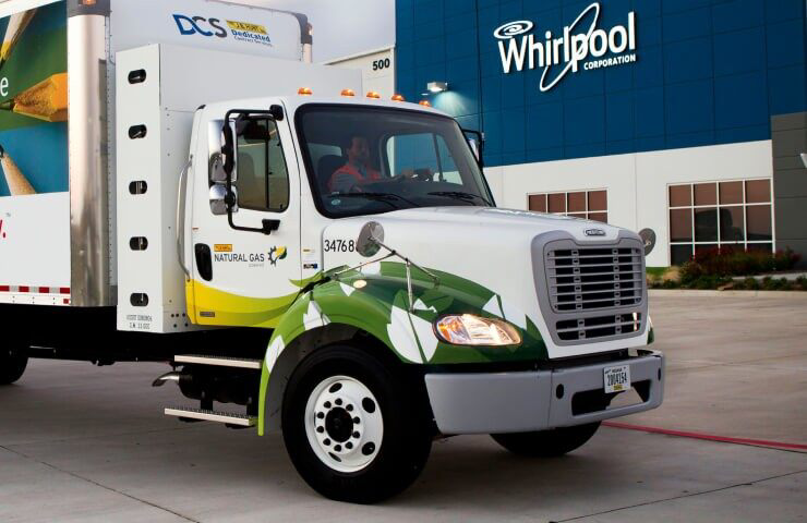 A Whirlpool delivery truck in the yard of a Whirlpool building.