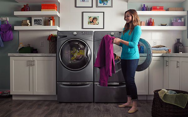 A person getting clothing out of a washer or dryer.