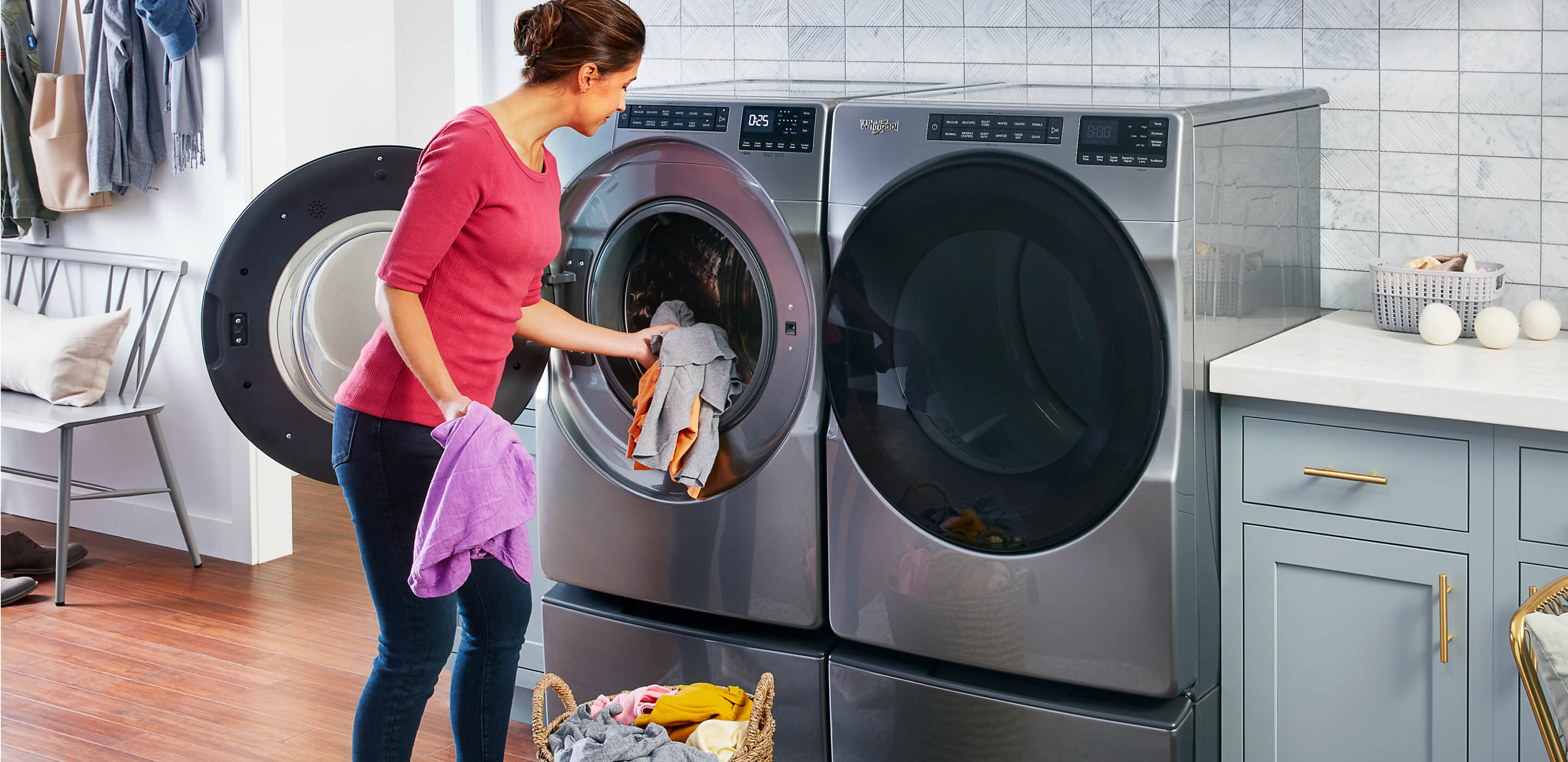 A person loading laundry into a Whirlpool® Front Load Washer and Dryer Pair