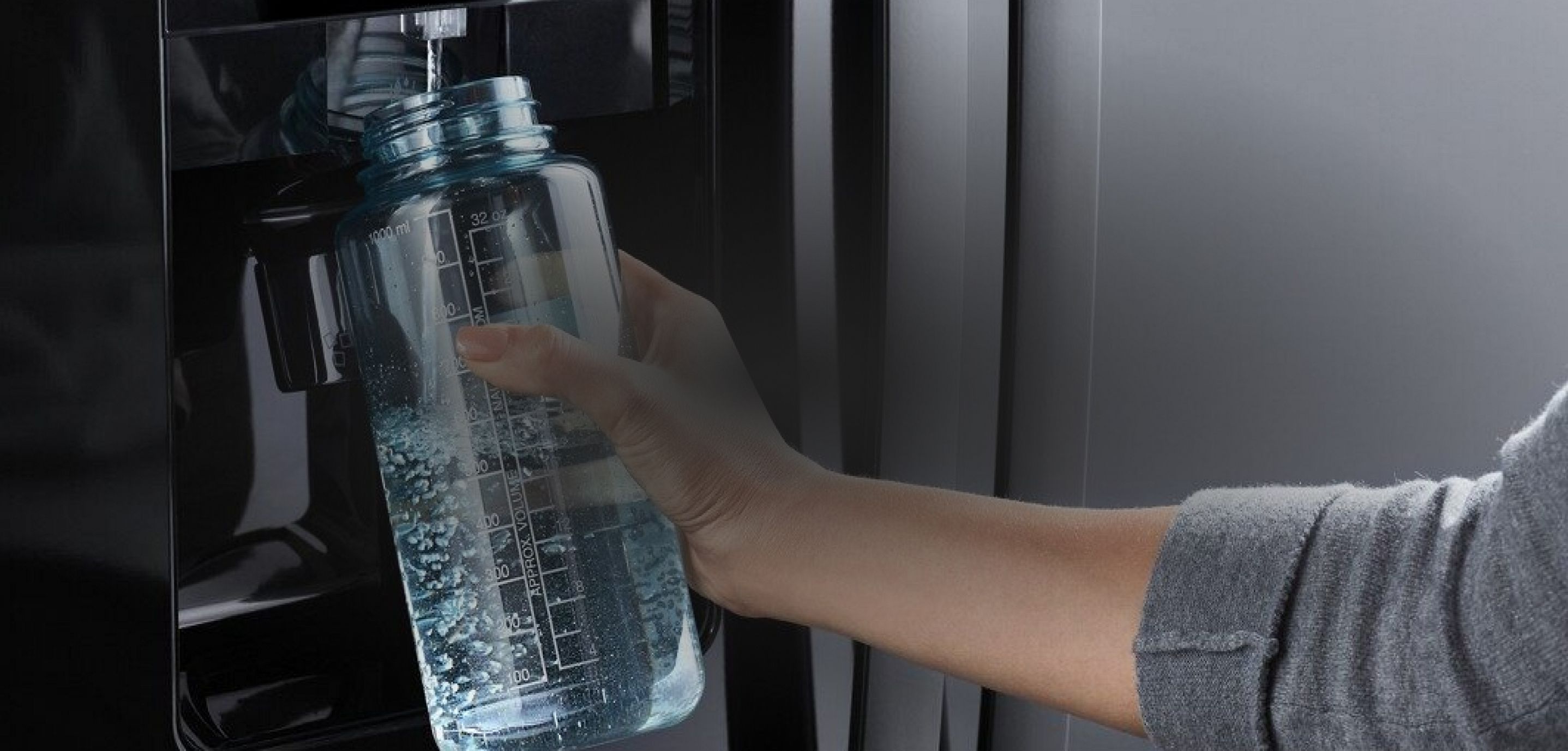 Person filling a reusable water bottle from the fridge