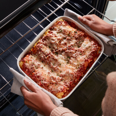 Person removing lasagna from the oven