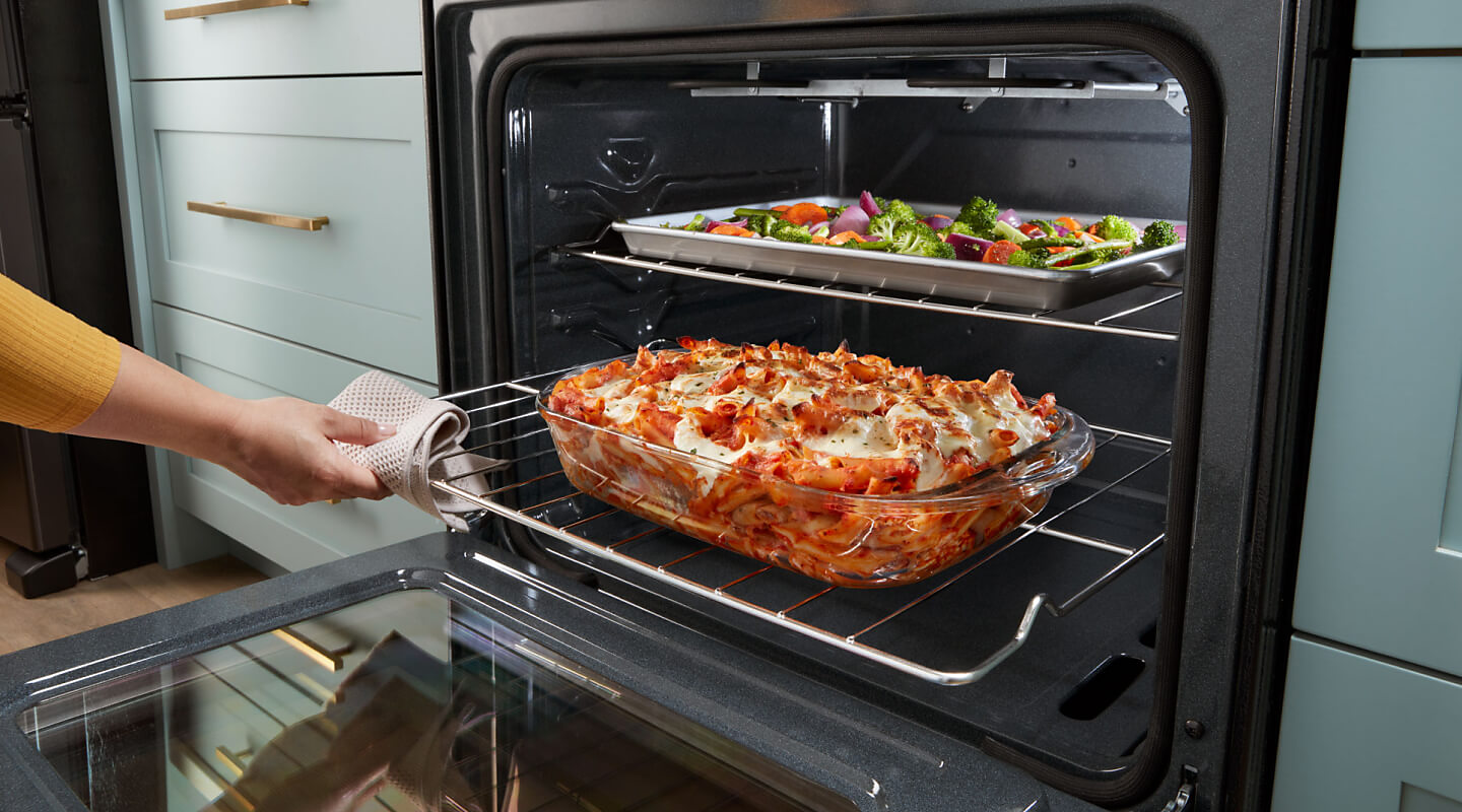 Person sliding out lower oven rack with lasagna on top 